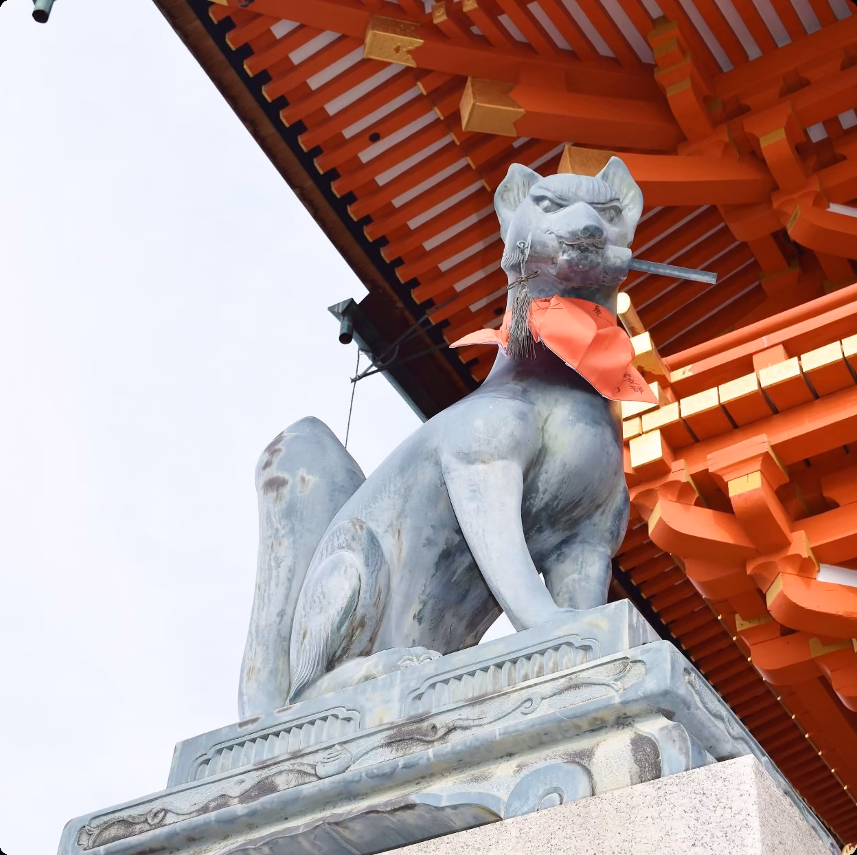 A stone fox statue wearing a red bib at Fushimi Inari Taisha